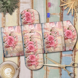 May include: A paper craft project featuring a floral design with pink roses and white accents. The design is printed on a multi-panel template, with cut lines visible. The background is a distressed, pastel-colored wood surface. A pair of scissors and a cup of coffee are also visible.