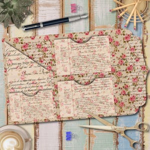 Może przedstawiać: Kieszeń z papieru w stylu vintage z kwiatowym wzorem róż i francuskim pismem. Kieszeń jest otwarta, odsłaniając mniejsze kieszenie w środku. Pióro, nożyczki i artykuły papiernicze są wokół niej ułożone.