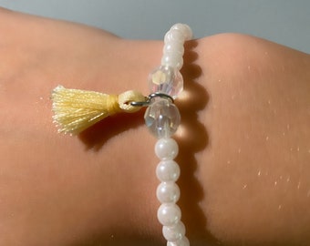 Perlenarmband mit weißen Perlen, klaren Perlen und gelber Quaste. Dehnbare, einheitsgröße passt am meisten.