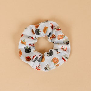 Könnte beinhalten: Ein blauer und weißer Haargummi mit einem Muster aus Katzen, die Weihnachtsmützen und andere festliche Accessoires tragen.