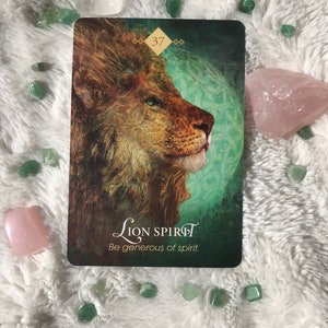 May include: A green and gold tarot card with a lion's head on the front. The card number 37 is in the top right corner. The text on the card reads "Lion Spirit" and "Be generous of spirit."