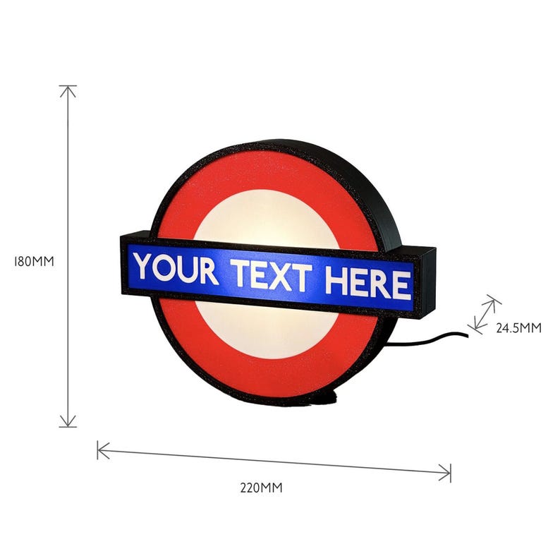 May include: A circular wall sign featuring a red ring and a central white circle, bisected by a horizontal blue rectangular bar with the white text "YOUR TEXT HERE". The sign measures 180mm in height, 220mm in width, and 24.5mm in depth.