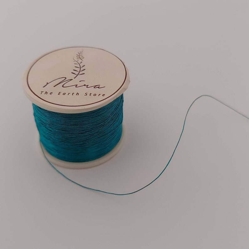 May include: A spool of teal thread with a label that reads "Mira The Earth Store"