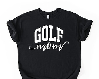 May include: A black short-sleeved t-shirt featuring the white text GOLF in a bold, block-style font positioned above the word mom written in a white, flowing cursive script. The shirt has a crew neckline and rolled sleeves.