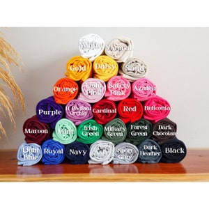 Może przedstawiać: Kolekcja zwiniętych pr&oacute;bek tkanin w r&oacute;żnych kolorach, w tym biały, naturalny, złoty, stokrotka, piaskowy, pomarańczowy, jasnor&oacute;żowy, r&oacute;żowy bezpieczeństwa, azalia, fioletowy, promienny storczyk, kardynał, czerwony, heliconia, bordowy, miętowy, zielony irlandzki, zielony wojskowy, zielony leśny, ciemna czekolada, jasnoniebieski, kr&oacute;lewski niebieski, granatowy, popielaty, szary sportowy, ciemny szary i czarny.