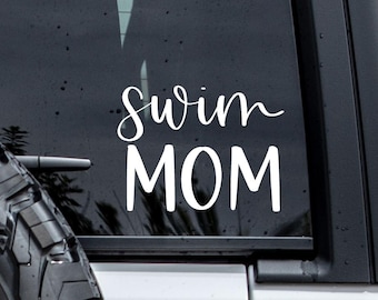 May include: White vinyl decal with the text "Swim Mom" on a black car window.