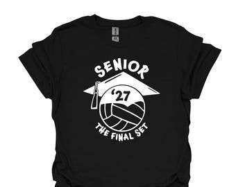 May include: A black short-sleeve t-shirt featuring a white graphic design of a graduation cap above a volleyball. The text reads SENIOR, '27, and THE FINAL SET. The design is centered on the chest of the shirt, which has a standard crew neckline.