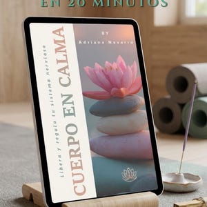 Puede incluir: Una tableta muestra la portada de un libro con una flor de loto rosa y piedras apiladas. El título dice "CUERPO EN CALMA" y "GUÍA PRÁCTICA: LIBERA TU ESPALDA EN 20 MINUTOS." La tableta está sobre un soporte de madera, con incienso y esterillas de yoga en el fondo.