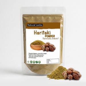 May include: A clear plastic stand-up pouch containing light brown Haritaki powder. The label features the text Natural Lanka, Haritaki POWDER, and Terminalia chebula, with an image of a wooden bowl of powder and several dried brown fruits.