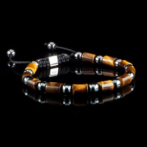 May include: A brown and black beaded bracelet with a silver clasp. The bracelet is made with tiger's eye and hematite beads.