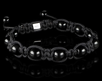 Puede incluir: Pulsera negra de cuentas con un cierre plateado marcado con "925". La pulsera está hecha con cordón negro y cuentas negras.