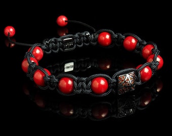 May include: A red gemstone bracelet with a black cord and a silver charm with black gemstones. The charm has a star-shaped design.