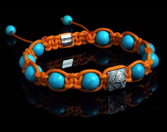 Può includere: Un braccialetto con perline turchesi e arancioni con un ciondolo d'argento a forma di diamante. Il braccialetto è realizzato con una tecnica di annodatura macramè.