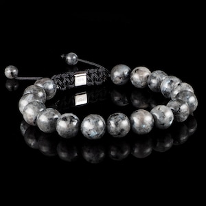 May include: A black beaded bracelet with a silver clasp and black cord. The beads are round and have a dark grey colour.
