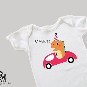 K&ouml;nnte beinhalten: Ein wei&szlig;er Baby-Strampler mit einem roten Auto und einem Dinosaurier, der einen Partyhut tr&auml;gt. Der Dinosaurier f&auml;hrt das Auto und der Text "ROARR!" ist auf dem Strampler aufgedruckt.