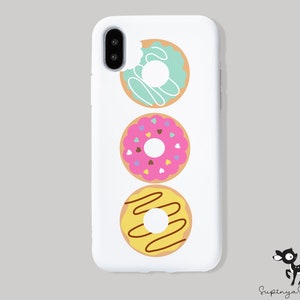 May include: White iPhone case with a vertical design of three donuts. The donuts are decorated with sprinkles, chocolate drizzle, and frosting.