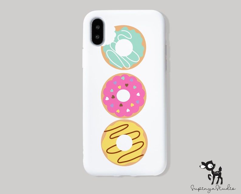 May include: White iPhone case with a vertical design of three donuts. The donuts are decorated with sprinkles, chocolate drizzle, and frosting.