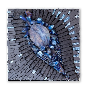 Könnte beinhalten: Ein Mosaik-Kunstwerk mit einem blauen Achat-Stein, umgeben von blauen und schwarzen Glassplittern. Das Kunstwerk ist in einem schwarzen Rahmen gefasst.