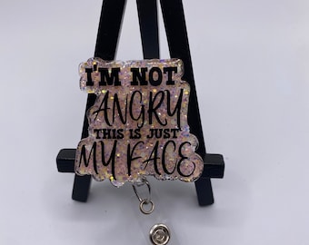 May include: A pink glitter badge holder with the text "I'm not angry this is just my face" in black lettering.