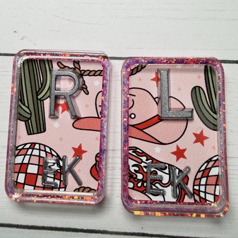 May include: Two rectangular resin coasters with a pink background featuring cowboy hats, cacti, and disco balls. Silver letters spell "R E K" and "L E K" on each coaster. The edges are outlined with glitter.
