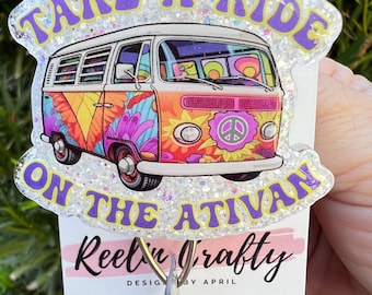 Pode incluir: Uma van psicodélica branca e colorida com o texto "Take a Ride on the Ativan" e "Reel'n Crafty" com um sinal de paz na frente. A van está em um fundo branco com glitter.