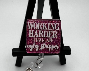 May include: Pink glitter badge holder with a white text overlay that reads "Working Harder -Than An- Ugly Stripper". The badge holder is attached to a clear retractable badge reel.