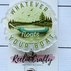 May include: A badge reel with a scenic illustration of a lake and trees, with the text "Whatever floats your boat" in green. The badge reel has a glittery, scalloped edge and a metal clip.