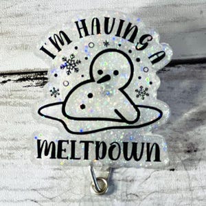 May include: A white glitter badge holder with a snowman melting and the text "I'm having a meltdown".