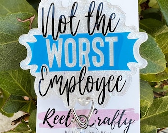 May include: A white and blue glitter badge holder with the text "Not the Worst Employee" and a blue ribbon. The badge holder is attached to a clear plastic retractable badge reel with a silver clip. The badge reel has the text "Reel Crafty Designs by April" and social media icons for TikTok, Instagram, and Facebook.