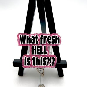 May include: Pink glitter badge reel with the text "What fresh HELL is this?!" in black lettering.