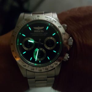 May include: A silver Invicta Professional 200M Chronograph watch with a black dial and luminous green accents. The watch features three sub-dials and a stainless steel strap. The watch face displays the Invicta logo and the words "Professional 200M Chronograph".