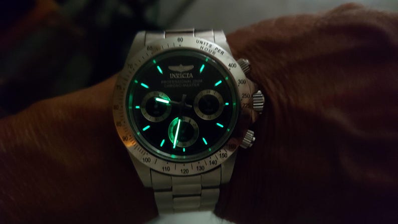 May include: A silver Invicta Professional 200M Chronograph watch with a black dial and luminous green accents. The watch features three sub-dials and a stainless steel strap. The watch face displays the Invicta logo and the words "Professional 200M Chronograph".