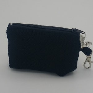 May include: A small black rectangular zippered pouch with a textured fabric surface. A silver-toned metal charm shaped like a bat is attached to the zipper pull, along with a silver-toned metal lobster clasp for easy attachment to other items.