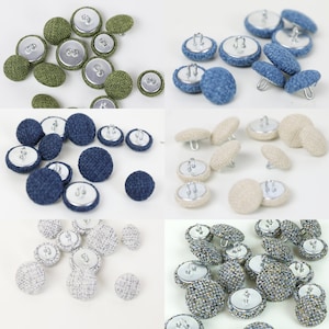 Può includere: Assortimento di bottoni rivestiti in tessuto di vari colori, tra cui verde, blu, beige e grigio. I bottoni sono rotondi e hanno un retro piatto. Alcuni bottoni hanno un gambo, mentre altri hanno dei fori.