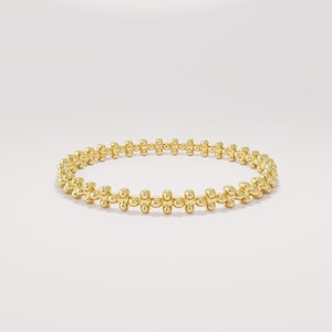 Könnte beinhalten: Ein goldfarbenes Armband mit Perlenmuster. Das Armband ist kreisförmig und weist eine Reihe kleiner, runder Perlen auf, die miteinander verbunden sind. Die Perlen haben eine glänzende, reflektierende Oberfläche. Das Armband wird auf weißem Hintergrund präsentiert.