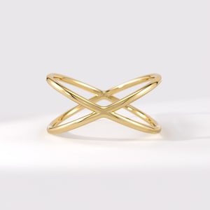 Könnte beinhalten: Ein polierter Goldring mit einer glatten, durchgehenden Ringschiene, die sich kreuzt und eine X-förmige Silhouette bildet. Das Metall hat eine reflektierende, hochglänzende Oberfläche mit abgerundeten Kanten für ein schlichtes Design.