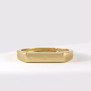 May include: A polished gold ring with a flat, rectangular top surface. The band features a smooth, reflective finish and includes the engraved text 14K on the inner surface of the ring, showcasing a clean, solid metal construction throughout.