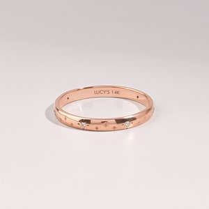 14k solid rose gold 2mm wedding band with engraved with tiny stars and flush setted G Colour SI Clarity genuine diamonds on a white background