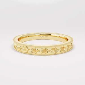 May include: A gold 14k band with a delicate floral design. The band is engraved with "LUCY'S 14K".