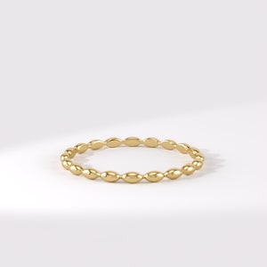 May include: A thin gold ring featuring a continuous band of small, polished, oval-shaped beads linked together in a circular design. The metal has a bright, reflective finish, creating a smooth and uniform appearance throughout the entire jewellery piece.