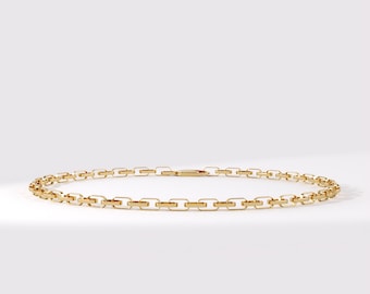 May include: A gold chain necklace featuring a series of uniform, elongated rectangular links connected in a continuous loop. The metal has a polished, reflective finish, and the design includes a small, integrated clasp mechanism for closure.