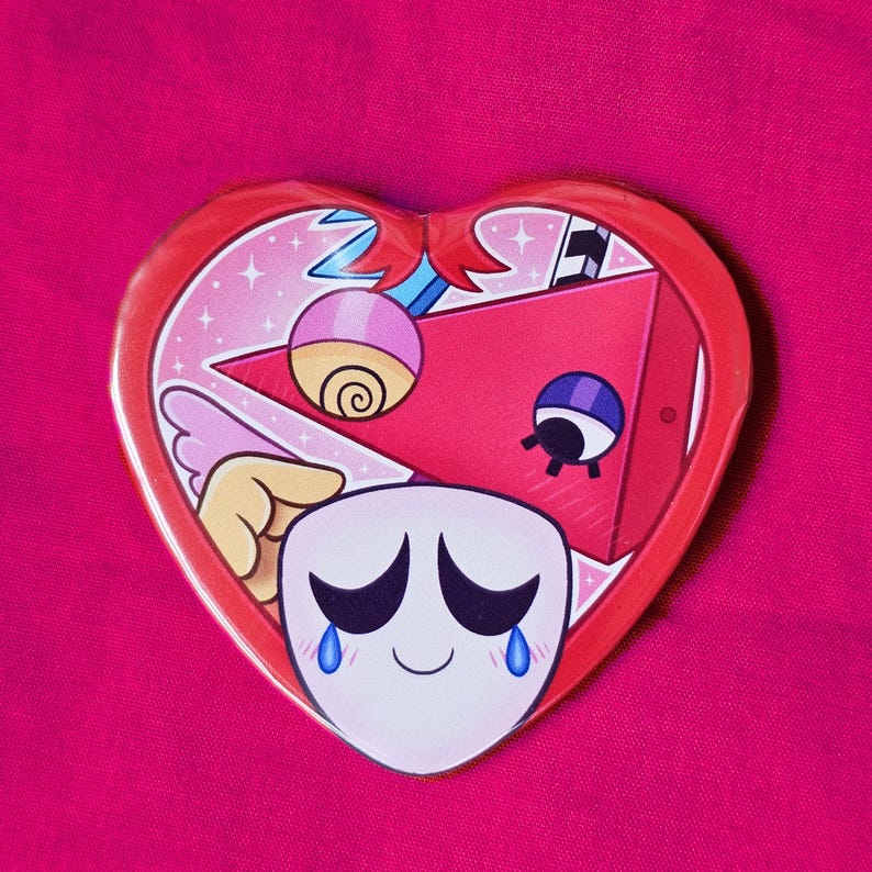 May include: A heart-shaped badge with a red border and a cartoon design. The design features a white face with black eyes and blue tears, a red triangle, and other colourful elements. The background is pink.