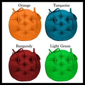 May include: Four round chair cushions in different colours: orange, turquoise, burgundy, and light green. Each cushion has a tie on each side.