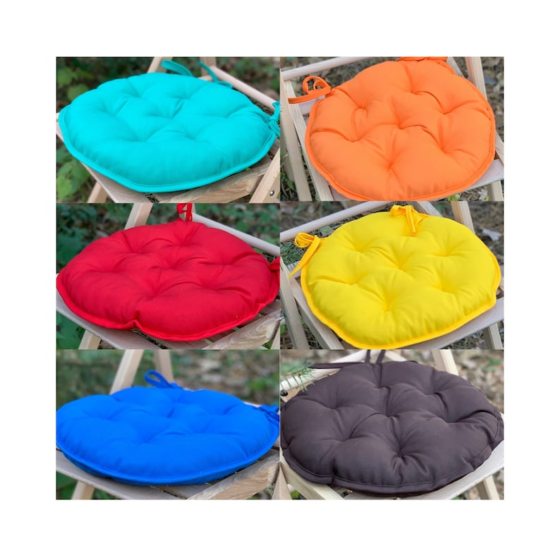 May include: Set of six round chair cushions in various colours, including turquoise, orange, red, yellow, blue, and brown. The cushions have a tufted design and are tied with a string.