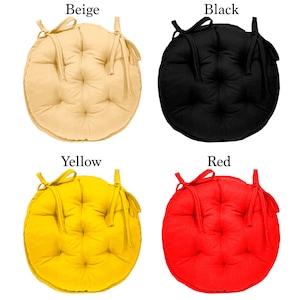 May include: Four round chair cushions in different colours: beige, black, yellow, and red. Each cushion has a tied bow and a button tufted design.