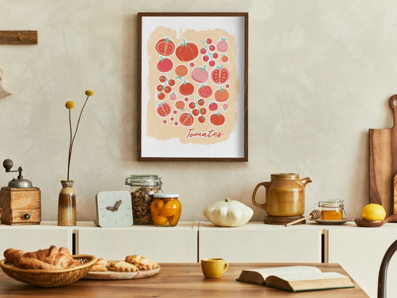 Pu&ograve; includere: Una stampa incorniciata con un'illustrazione colorata di pomodori in varie tonalit&agrave; di rosso e rosa. La stampa &egrave; su uno sfondo beige chiaro con la parola "Pomodori" scritta in un carattere stilizzato in basso. La stampa &egrave; appesa a una parete beige chiaro sopra un bancone con vari oggetti da cucina.