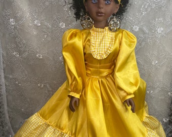May include: A yellow doll wearing a yellow and white gingham dress, a yellow crown with gold accents, and large gold earrings. The doll has dark skin and blue eyes.
