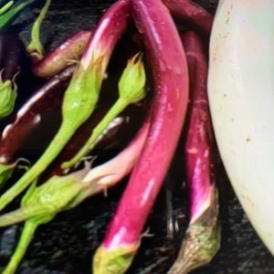 May include: A bunch of purple eggplants with green stems. The eggplants are arranged in a cluster, with the stems pointing upwards.
