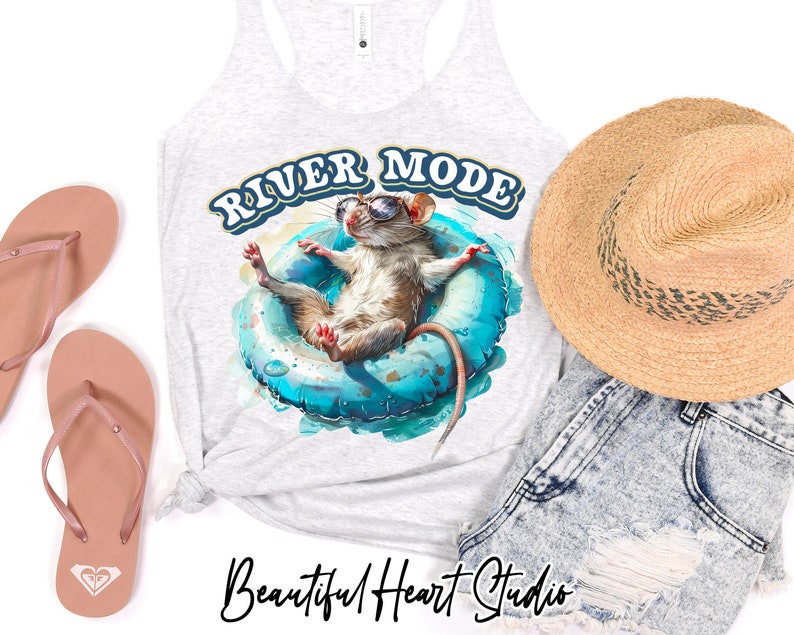 Puede incluir: Una camiseta sin mangas gris con el texto "River Mode" en letras azules y blancas. Un rat&oacute;n de dibujos animados con gafas de sol flota en un flotador inflable azul. El rat&oacute;n es marr&oacute;n con la barriga blanca. La camiseta sin mangas est&aacute; sobre un fondo blanco con un par de chanclas rosas y un sombrero de paja.