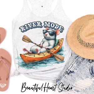 K&ouml;nnte beinhalten: Hellgraues Tanktop mit einer Grafik einer wei&szlig;en Ratte mit Sonnenbrille, die Kajak f&auml;hrt. Der Text "RIVER MODE" steht &uuml;ber der Ratte. Die Worte "Beautiful Heart Studio" sind unten in Kursivschrift geschrieben.
